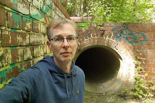 Mark Ridyard beside a sewage outfall pipe