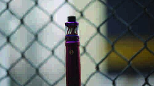 Vape in front of a chain link fence
